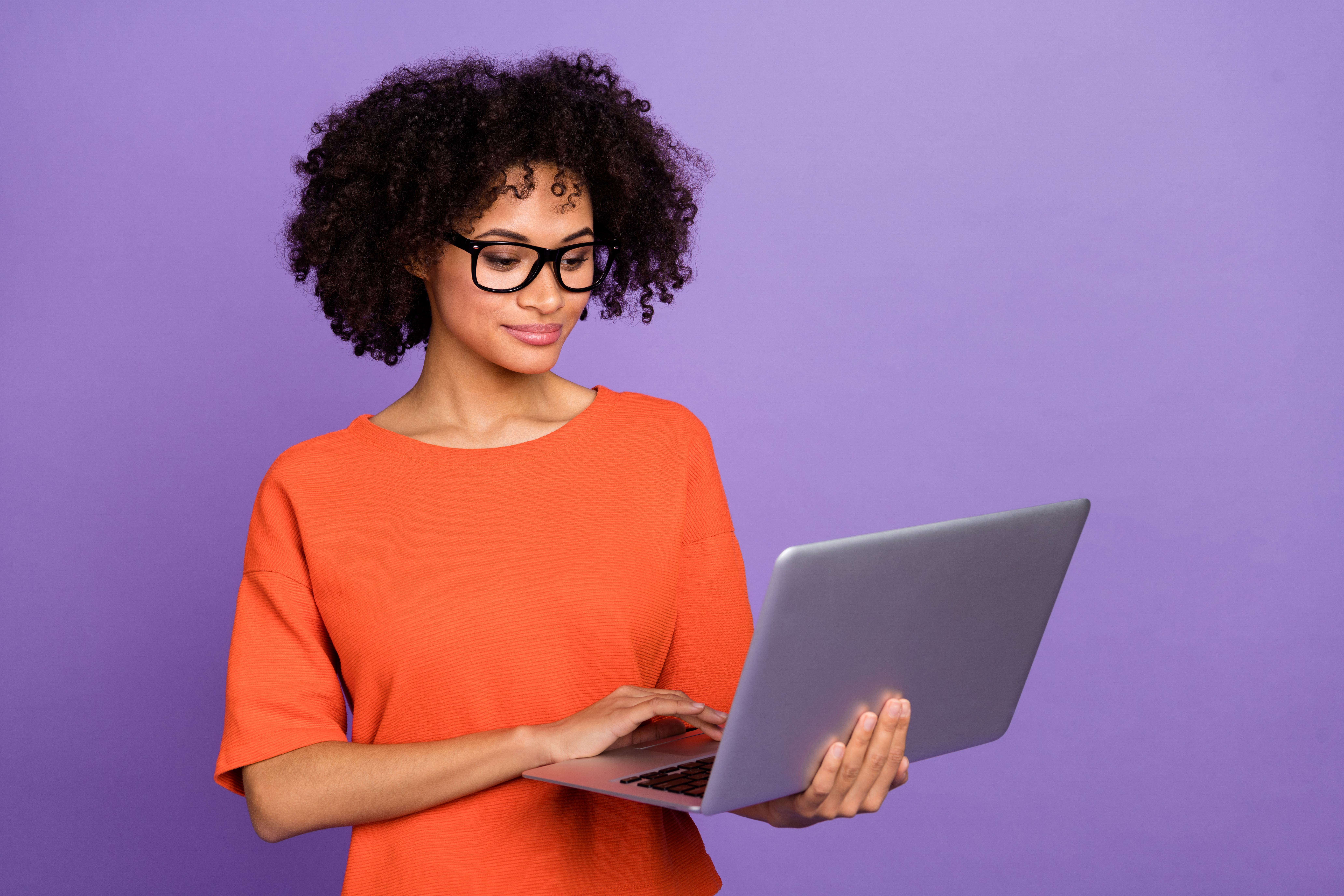 Photo of clever young lady type laptop wear orange t-shirt isolated on violet color background